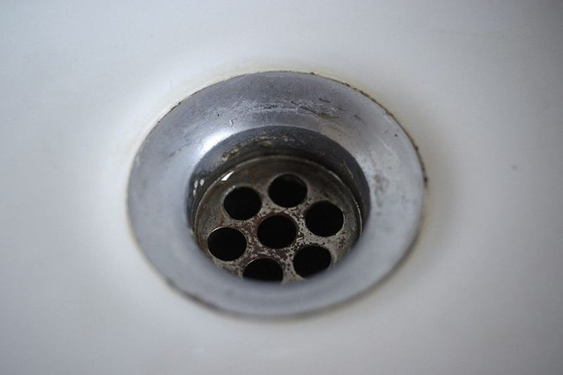 Close-up of a white washbasin plug hole, a blocked drain