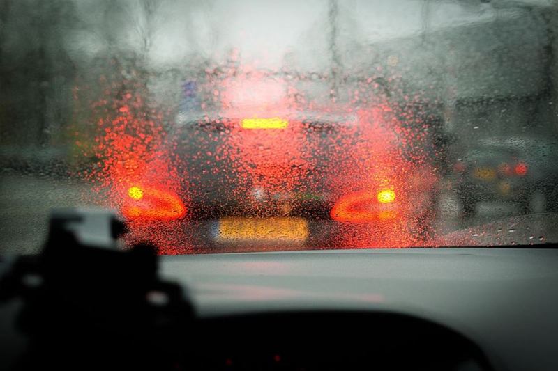 Vista desde el interior a través del parabrisas mojado y empañado de un coche