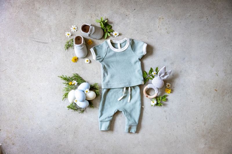 Conjunto de bebé azul claro con camiseta, pantalón y patucos en el suelo