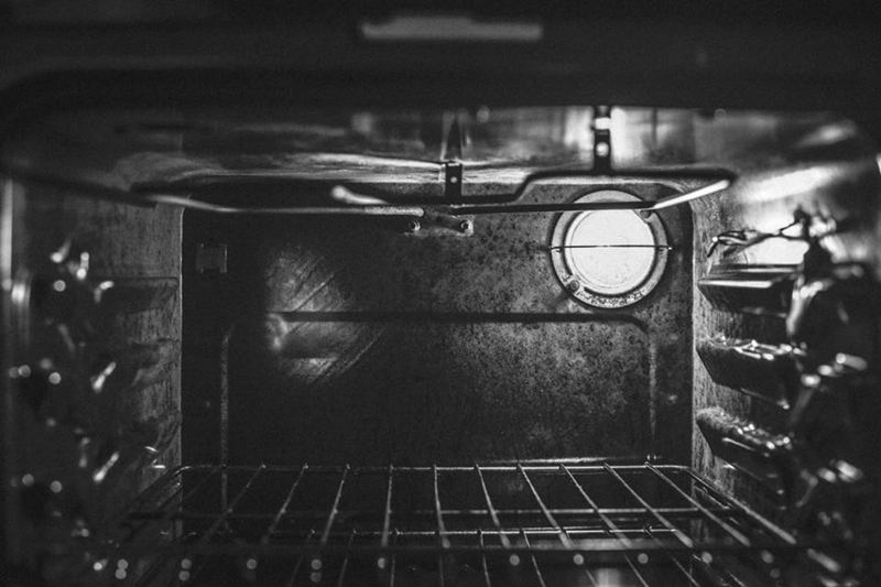Inside view of an oven with rack and light before oven cleaning