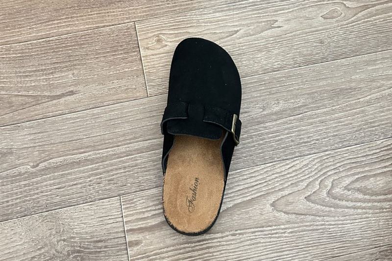 Zueco negro de ante con plantilla de corcho sobre un suelo de madera claro