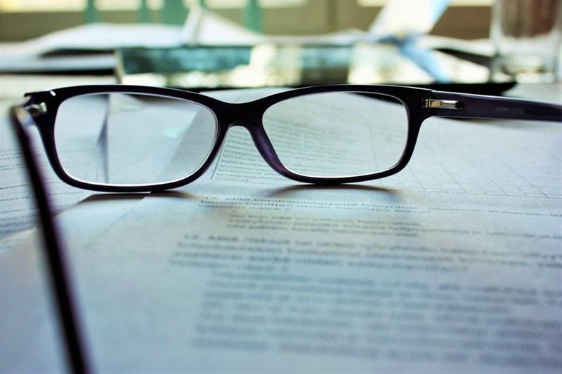 Gafas negras sobre una hoja de papel, con cristales que limpiar sin rayar