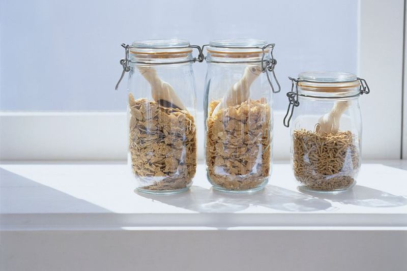 Tres tarros herméticos de cereales en un alféizar, contra la carcoma del pan