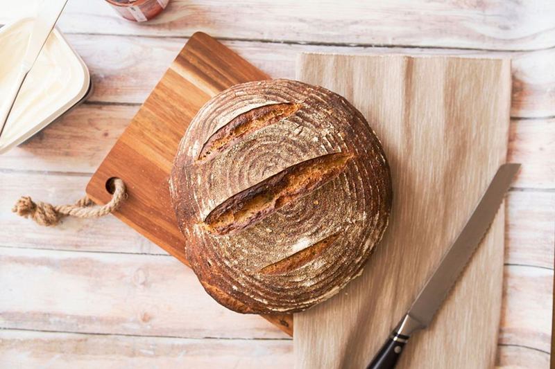 Hogaza de masa madre sobre una tabla de madera con cuchillo de pan