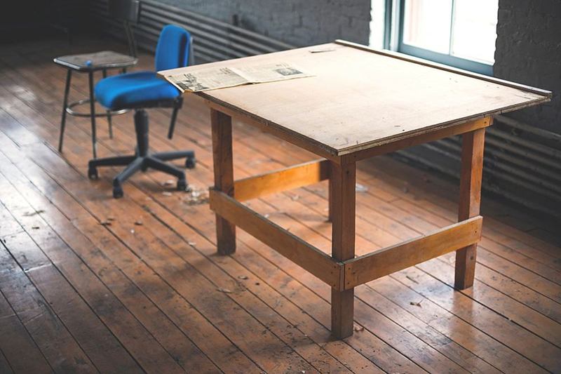 Silla de oficina azul con ruedas junto a una mesa de madera