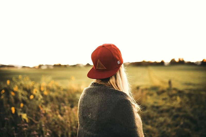 Gorra de béisbol roja vista desde atrás, en un campo con luz de atardecer