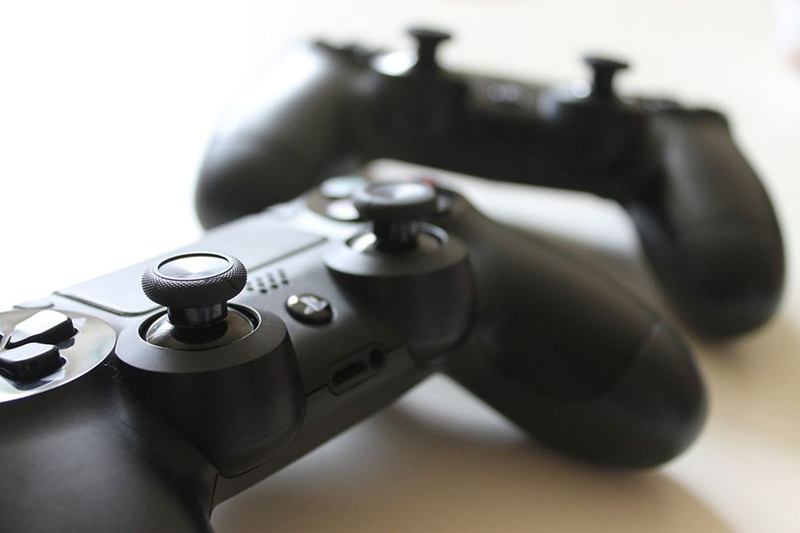 Dos mandos de juego negros con palancas analógicas y botones sobre fondo claro