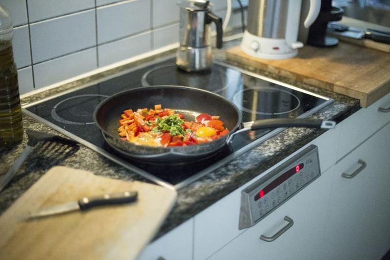 Pan on a hob in a bright kitchen, where grease clogs the hood filter