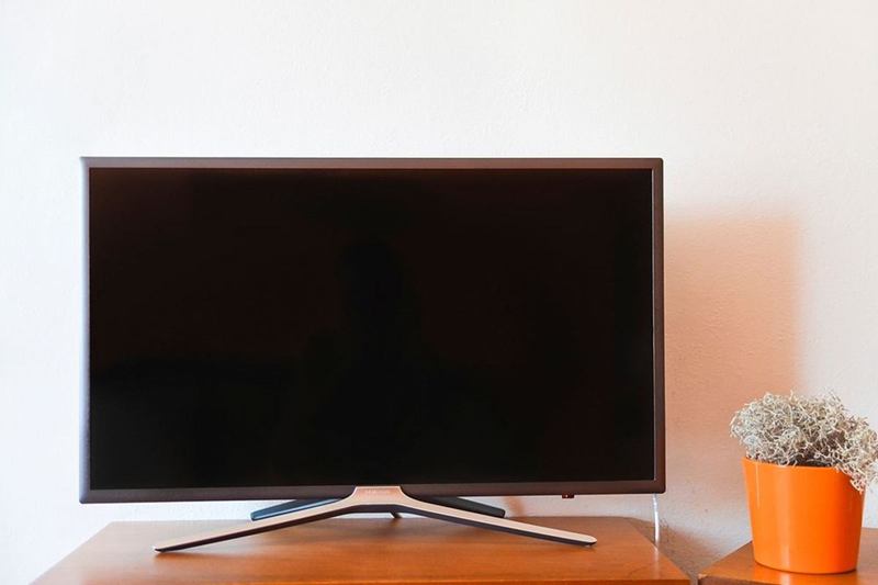 Televisor de pantalla plana sobre un mueble de madera, pantalla sin rayas