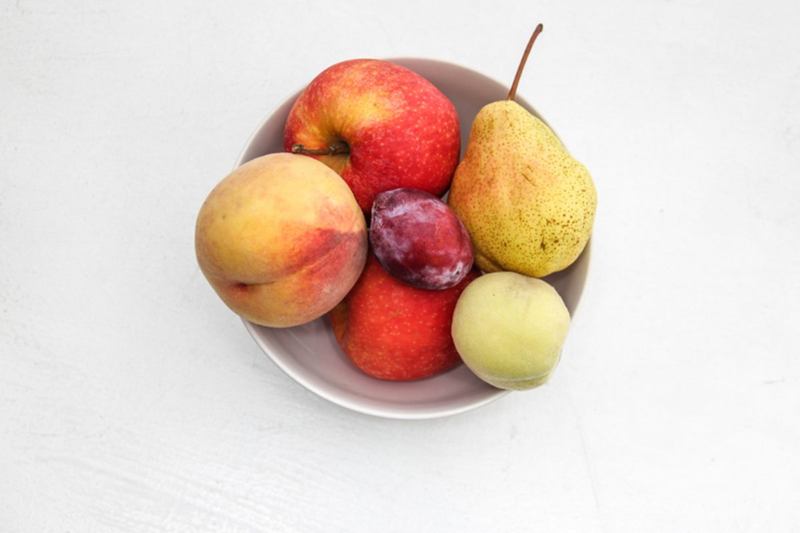 Bowl of ripe fruit with peach, apple, plum and pear that attracts fruit flies