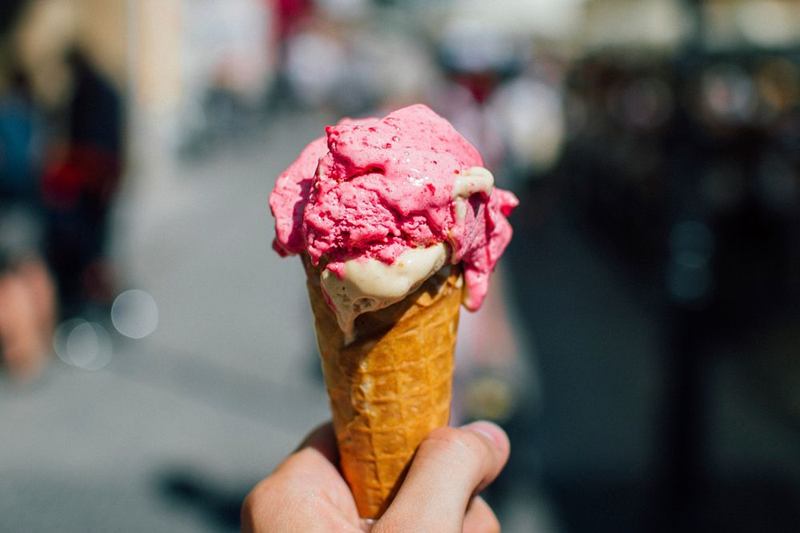 Mano con un cucurucho de helado de fresa que se está derritiendo
