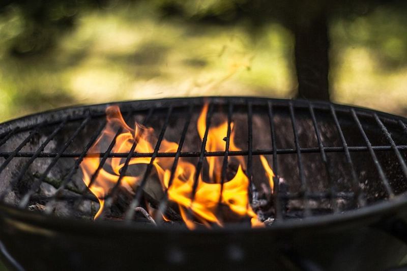 Charcoal grill with grate and flames before cleaning the grill