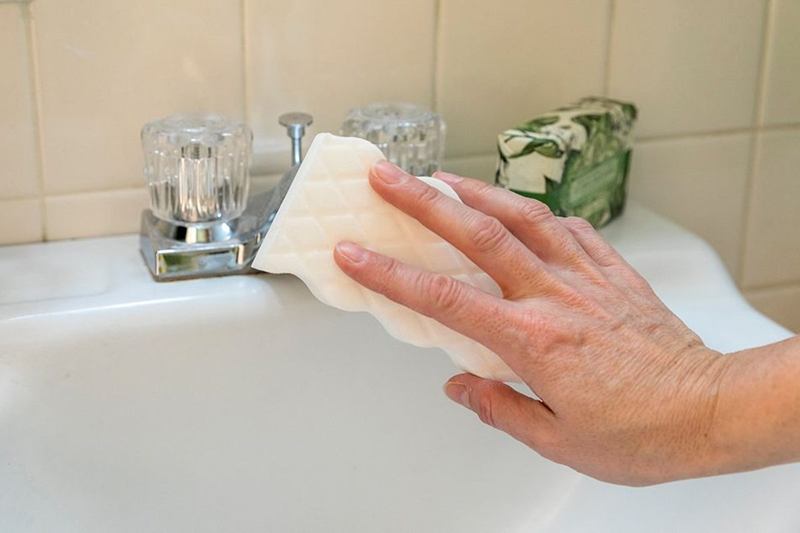 Main nettoyant le lavabo avec une éponge lors du grand nettoyage
