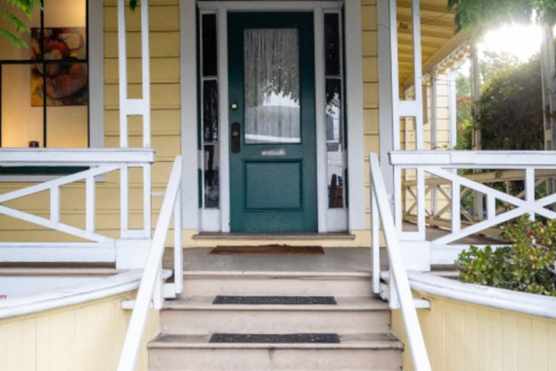 Entrée de maison avec escalier, paillassons et porte verte – nettoyer entrée et cage d'escalier en automne