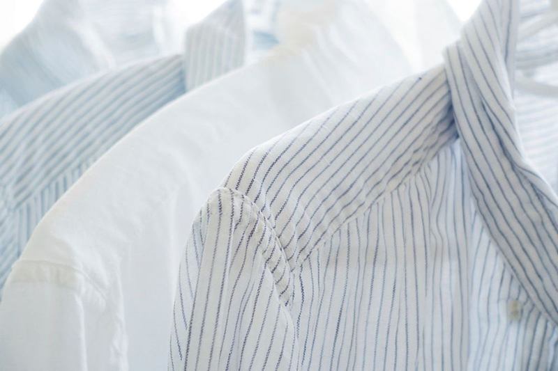 Camisas blancas y de rayas colgadas una junto a otra, recién lavadas
