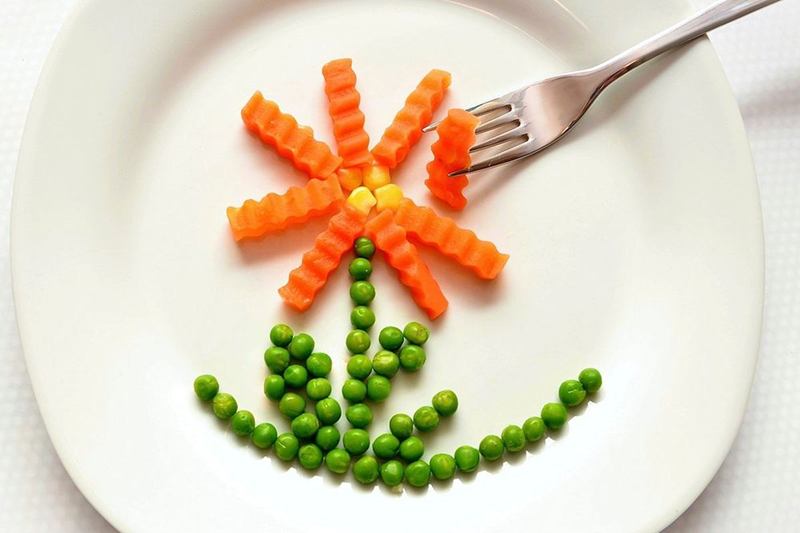 Plato infantil con verduras en forma de flor, servido en la trona