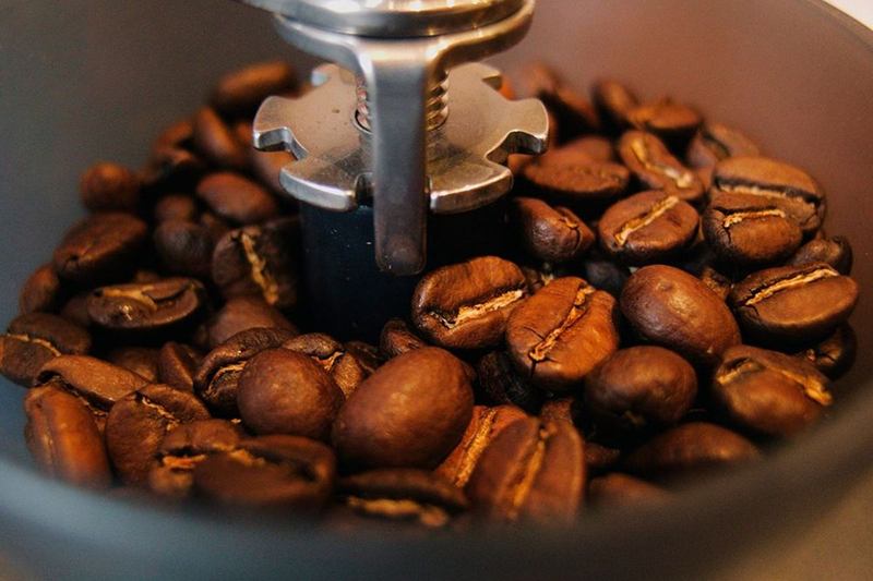 Café tostado en la tolva de un molinillo, alrededor del eje de la muela
