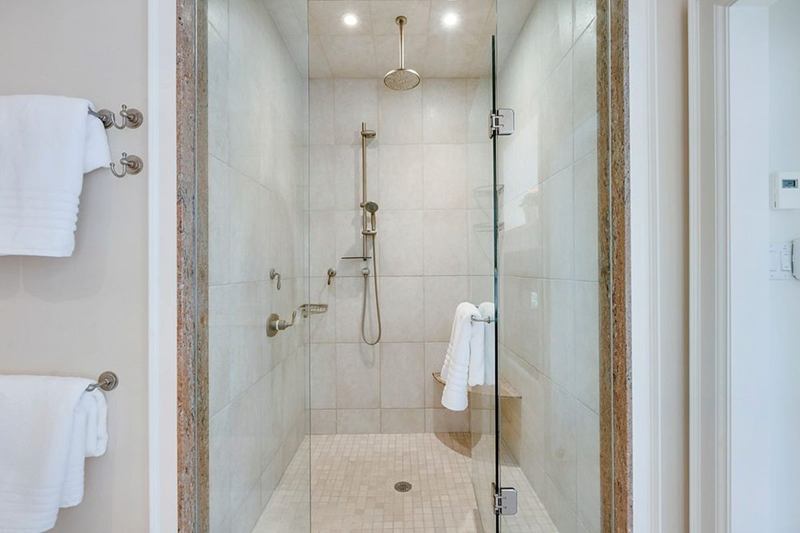 Walk-in glass shower with light tiles, free of limescale