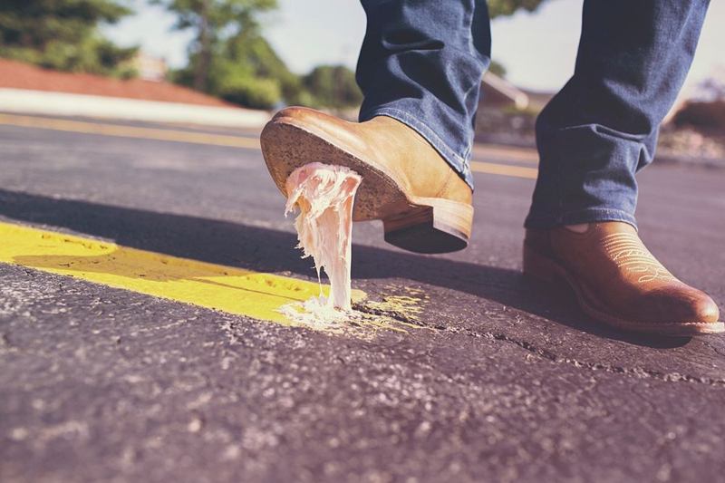 Zapato que pisa un chicle pegajoso que se estira bajo la suela