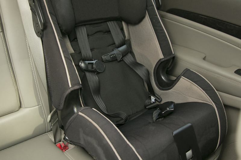 Silla infantil vacía con arnés en el asiento trasero de un coche