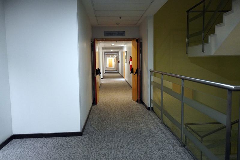 Pasillo luminoso de un edificio con escalera y barandilla, donde los carritos suelen estorbar