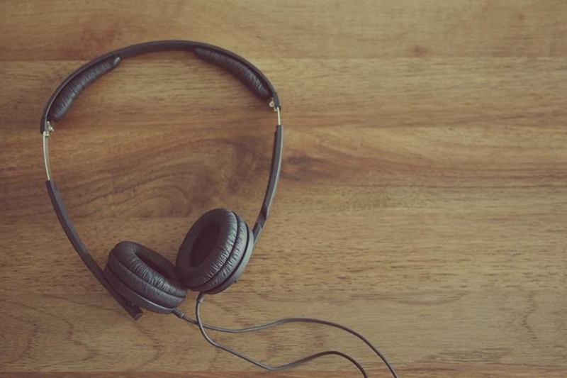 Auriculares de diadema con almohadillas y cable sobre una mesa de madera