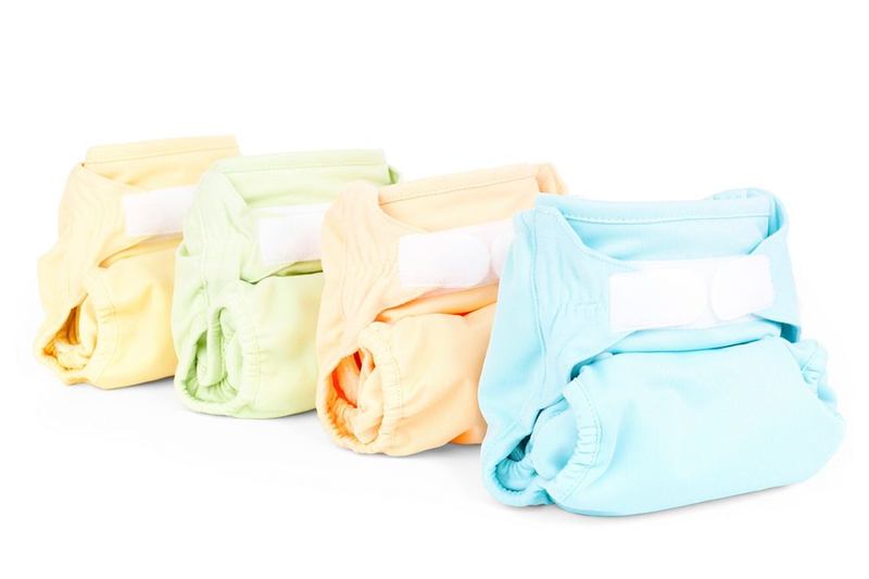Pañales de tela limpios en tonos pastel alineados tras quitar las manchas de caca