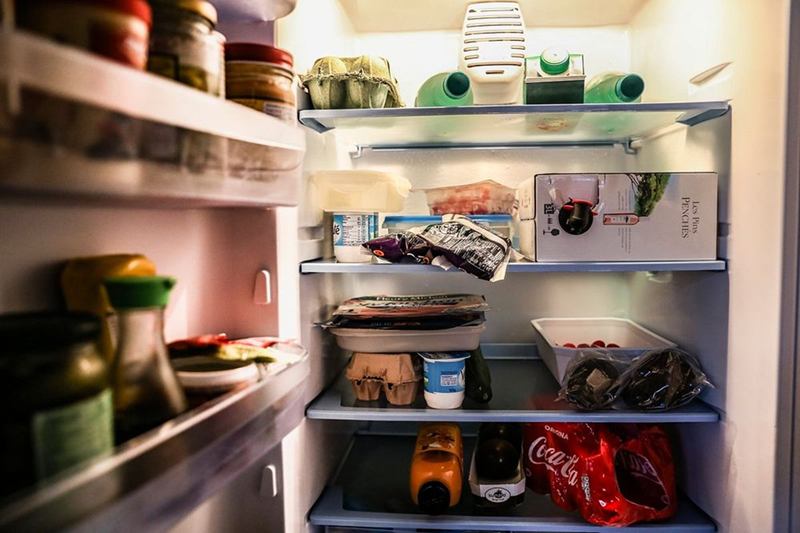 Open refrigerator stocked with food before cleaning the fridge