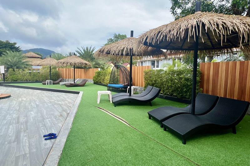 Jardín con césped artificial, tumbonas y sombrillas, limpio sin productos químicos