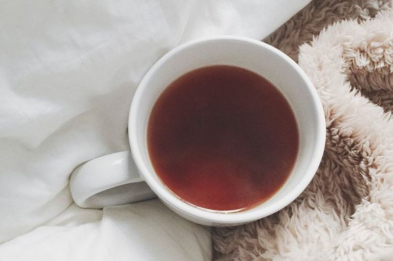 Taza de té sobre una mantita esponjosa de peluche en la cama