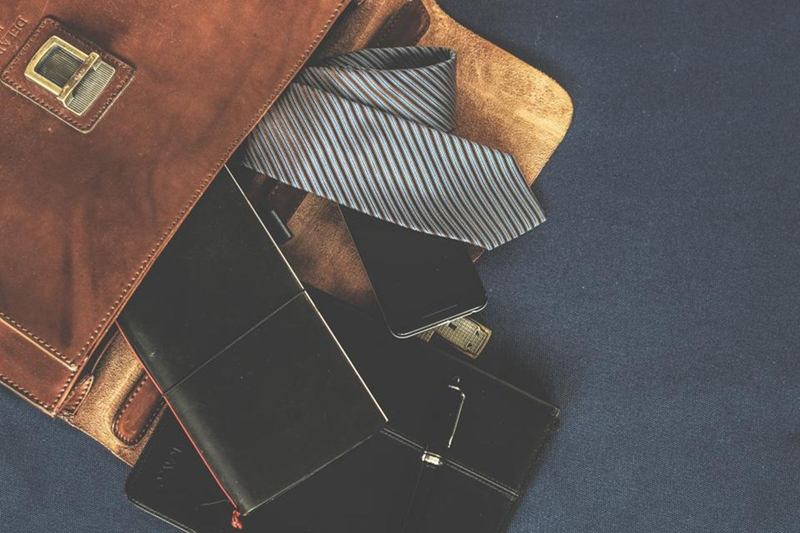 Bolso de piel lisa marrón abierto con una corbata y una cartera