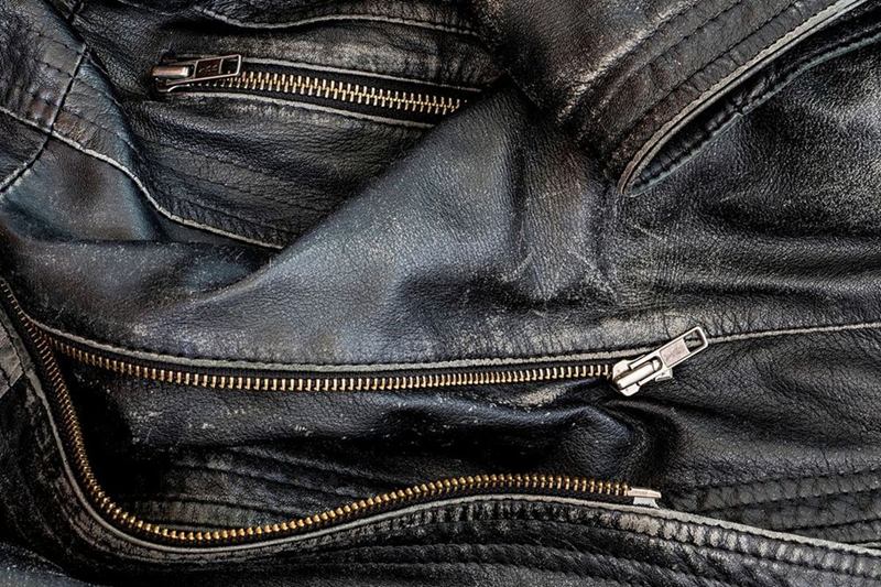 Primer plano de una chaqueta de cuero negra usada con cremalleras