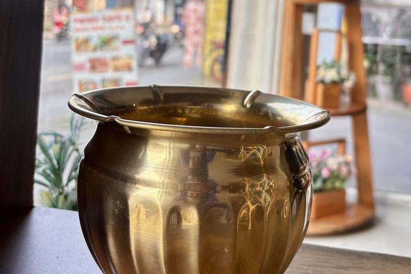 Olla de latón brillante decorada sobre una mesa de madera