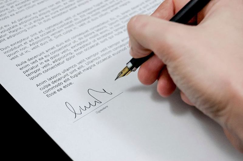 Mano que firma un contrato con una pluma estilográfica negra