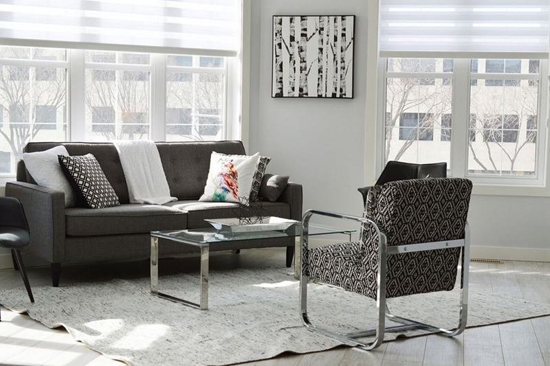 Salón luminoso y ordenado con sofá, sillones y mesa de cristal