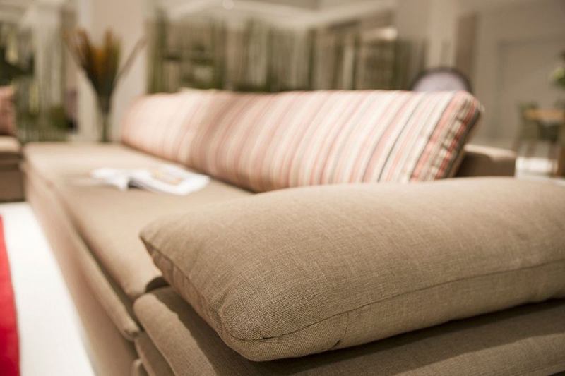 Sofá de tela beige con cojines y un cojín a rayas en el salón