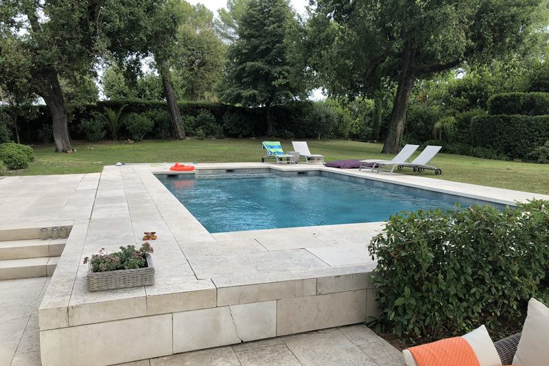 Piscina de jardín con agua cristalina entre césped y árboles tras limpiar la piscina