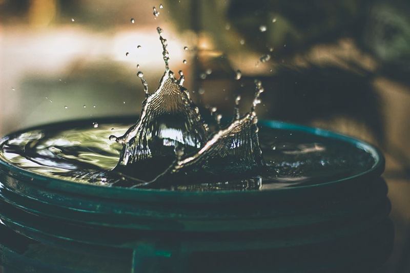 Agua salpicando en un barril lleno, como un depósito de agua de lluvia