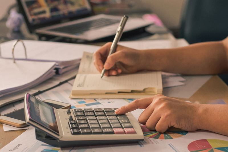 Hands with calculator and notes working out cleaning company costs