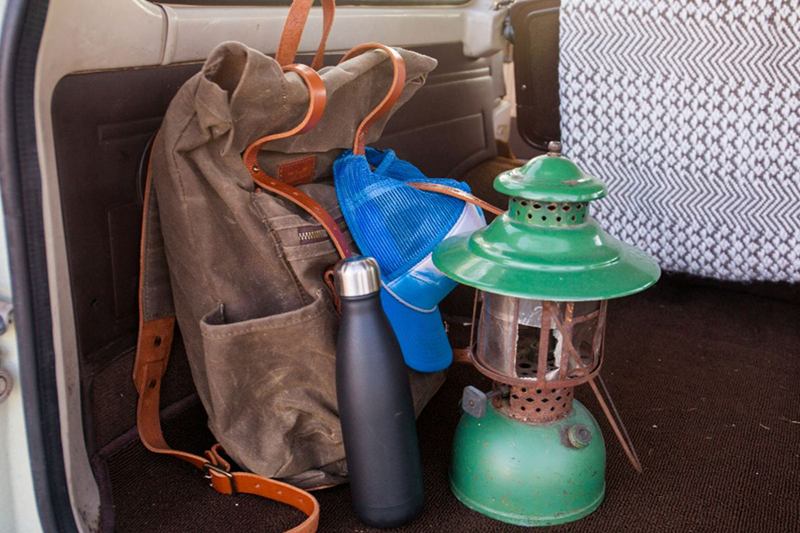 Mochila de lona con correas de cuero, botella y farol en el maletero