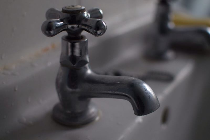 Grifo oscuro de cruceta en un lavabo, que requiere una limpieza suave