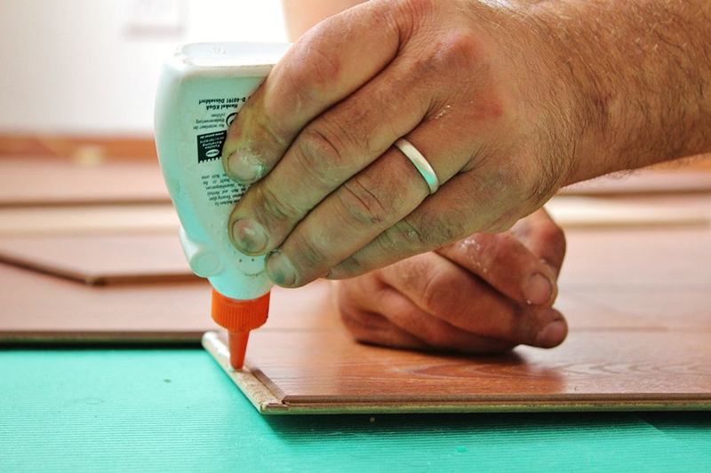 Mano aplicando pegamento sobre una tabla: los dedos pegados llegan enseguida
