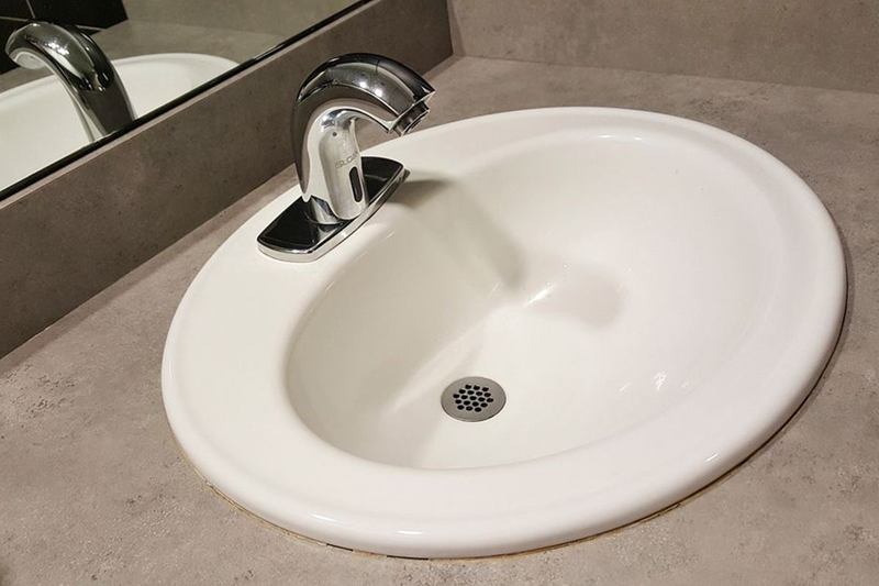 Lavabo blanco con grifo y desagüe, bajo el que está el sifón