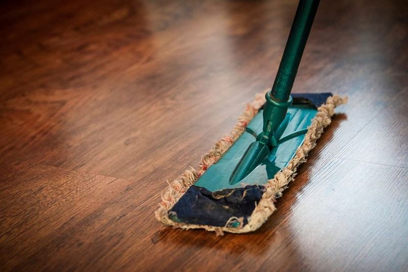 Flat mop on a shiny wooden floor during a move-out cleaning