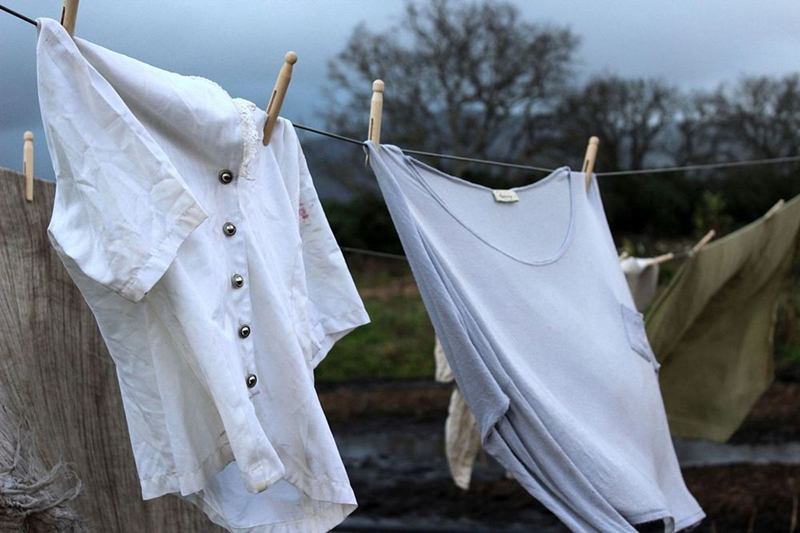 Ropa blanca con una camiseta interior secándose en el tendedero del jardín