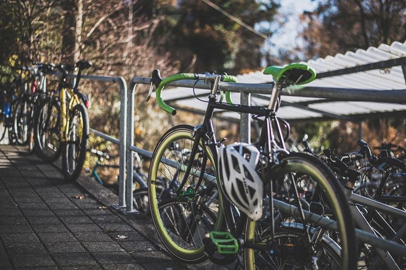 Casco de bicicleta blanco colgado de una bici aparcada en un aparcabicis