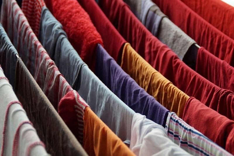Ropa de colores rojo, azul y morado secándose en el tendedero
