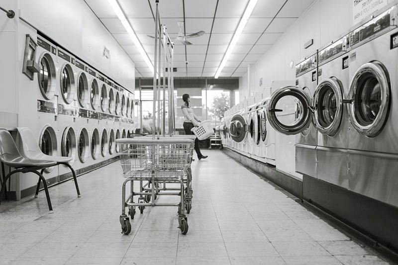 Laundry room with rows of washing machines and a laundry cart