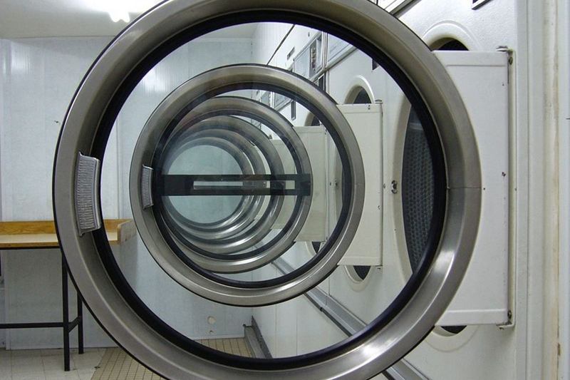 Vista a través de varias puertas abiertas de lavadoras en una lavandería