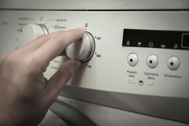 Mano que ajusta el programa de la lavadora antes de dosificar el detergente